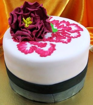Элегантный торт, украшенный пурпурным цветком и узорами