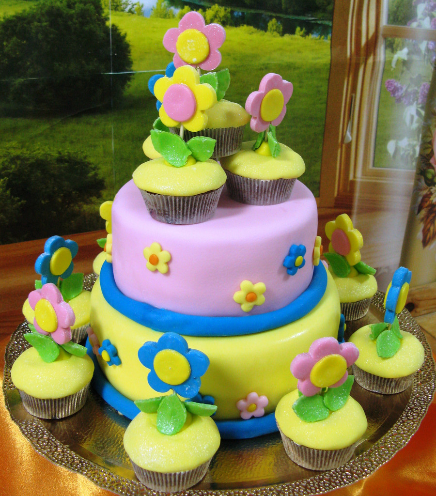 Яркий торт, украшенный капкейками с цветами из мастики